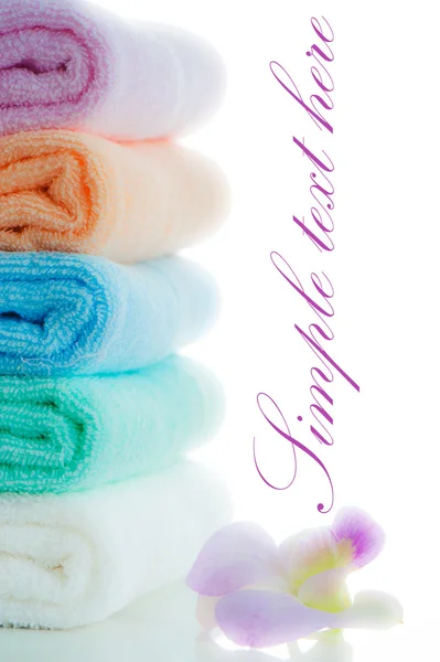 Multicolor towels stacked with a orchid flower on white backgrou — Stock Photo, Image