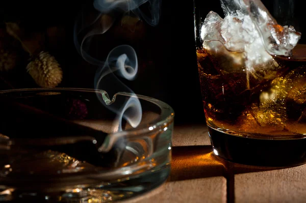 Ett glas whisky med en röka cigarr i askkoppen — Stockfoto