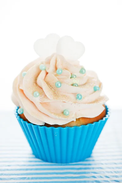 A cupcake in a blue baking cups with white cream, blue decoratio — Stock Photo, Image