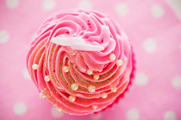 Ein Cupcake in einer rosa Backform mit rosa Sahne, weiße Dekoration — Stockfoto