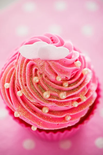 A cupcake in a pink baking cups with pink cream, white decoratio — Stock Photo, Image