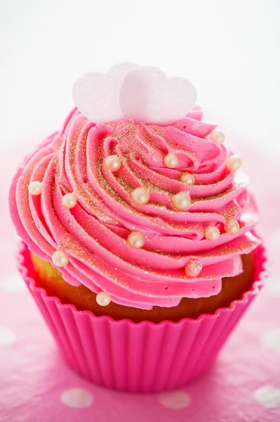 A cupcake in a pink baking cups with pink cream, white decoratio — Stock Photo, Image