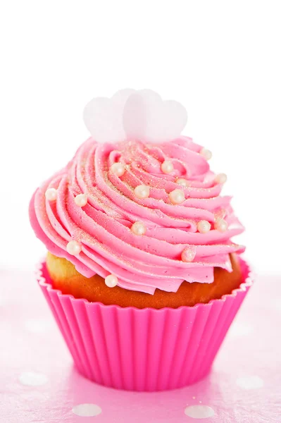 A cupcake in a pink baking cups with pink cream, white decoratio Stock Picture