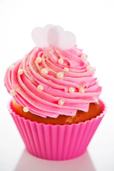 A cupcake in a pink baking cups with pink cream, white decoratio Stock Image