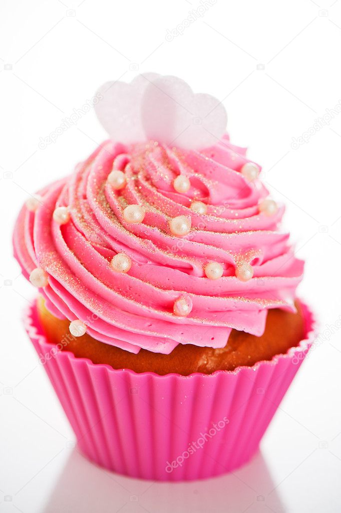 A cupcake in a pink baking cups with pink cream, white decoratio