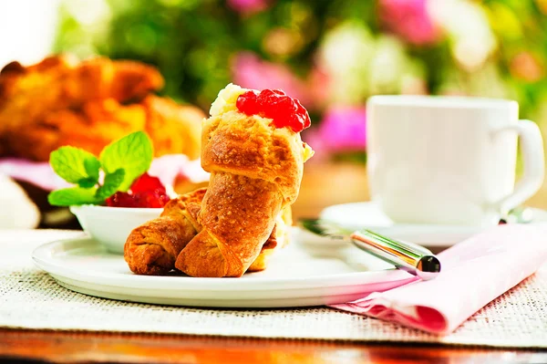 Desayuno al aire libre con café cruasán fresco, mermelada y flores a — Foto de Stock