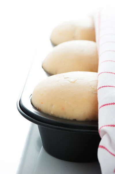 Yeast dough in a muffin pan with a white and red towel on white — Stock Photo, Image