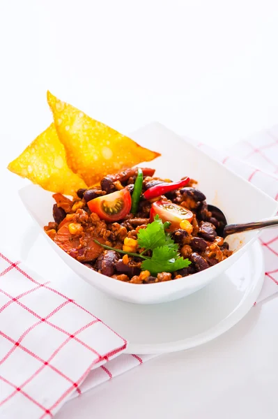 Chili con carne in a white bowl with two chips on white backgrou — Stock Photo, Image