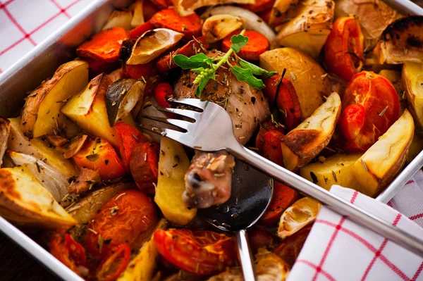 Chicken with vegetables on a baking tray as a studio shot — Stock Photo, Image
