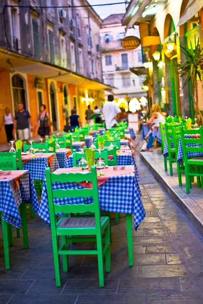 Táverna típica grega com mesas fora na rua da cidade mediterrânea de Corfu, cena noturna de rua — Fotografia de Stock