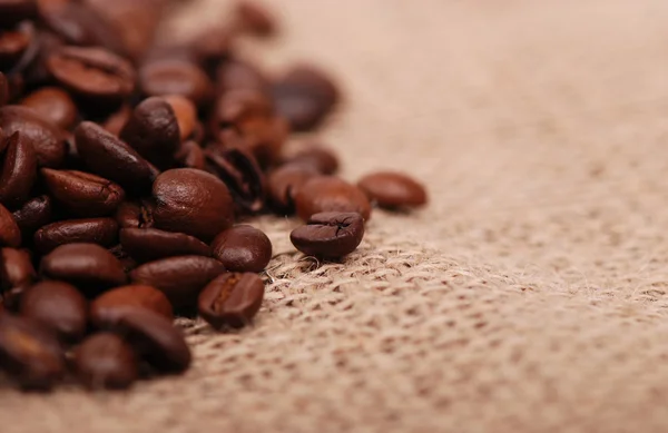 Tmavě kávová zrna nad plátnem — Stock fotografie