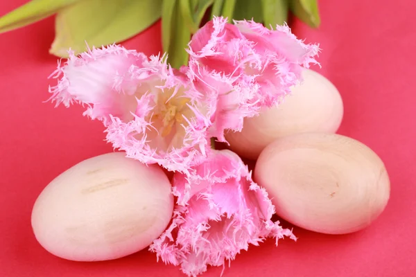 Alguns ovos de madeira e tulipas rosa — Fotografia de Stock