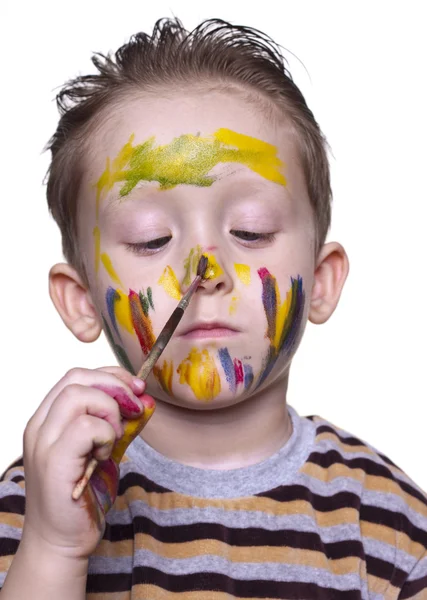 Um menino desenha no nariz com uma escova — Fotografia de Stock
