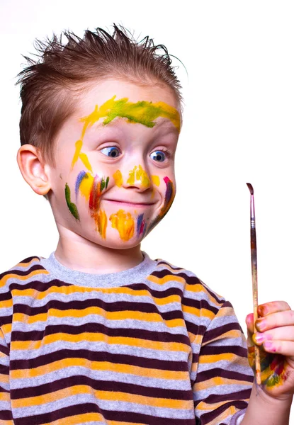 Un niño pequeño dibuja en la nariz con un cepillo Imagen de stock
