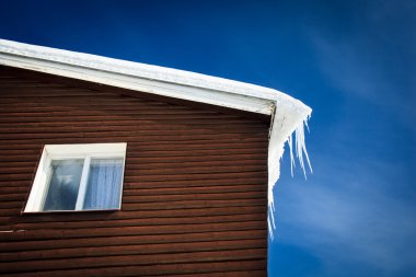 Closeup of a wooden cottage roof covered with snow clipart