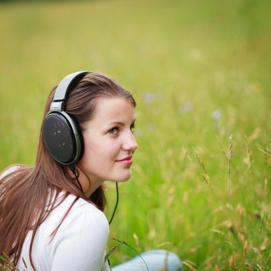 Portrait of a pretty young woman listening to music clipart