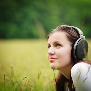 Portrait of a pretty young woman listening to music on her mp3 p clipart