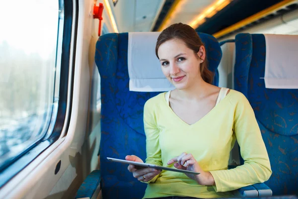 Молода жінка використовує свій планшетний комп'ютер під час подорожі поїздом — стокове фото