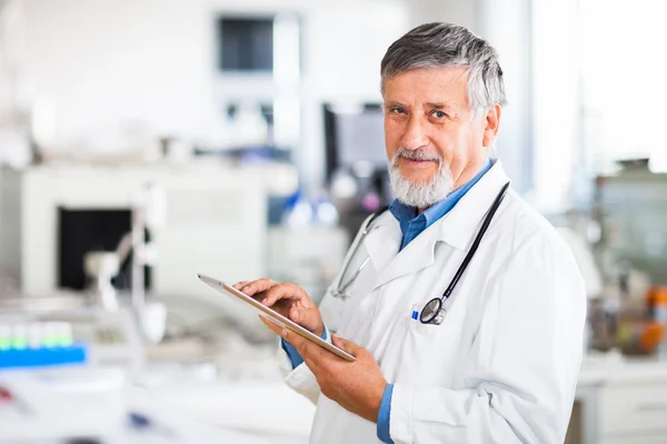 Senior arts met zijn tablet pc op het werk — Stockfoto