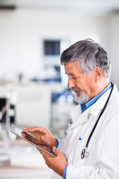 Senior arts met zijn tablet pc op het werk — Stockfoto