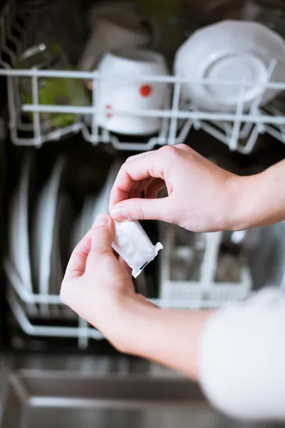 Οικιακές εργασίες: νεαρή γυναίκα βάζει πιάτα στο πλυντήριο πιάτων — Φωτογραφία Αρχείου