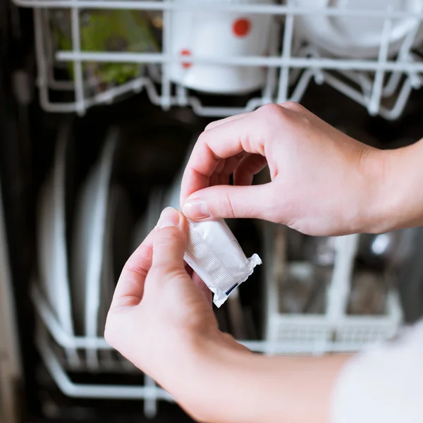 Prace domowe: młoda kobieta wkładająca naczynia do zmywarki — Zdjęcie stockowe