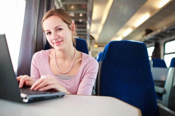Giovane donna che utilizza il suo computer portatile mentre sul treno (shallo — Foto Stock