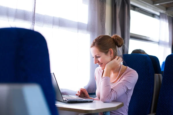 Jonge vrouw met behulp van haar laptopcomputer terwijl op de trein (shallo — Stockfoto