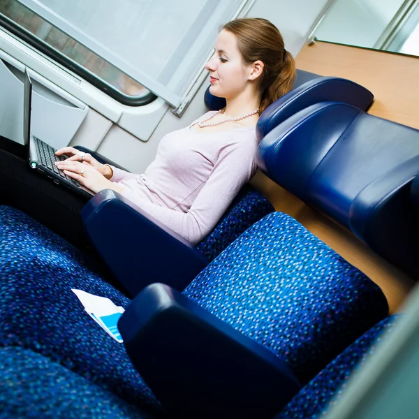 Mujer joven usando su computadora portátil mientras está en el tren (shallo — Foto de Stock