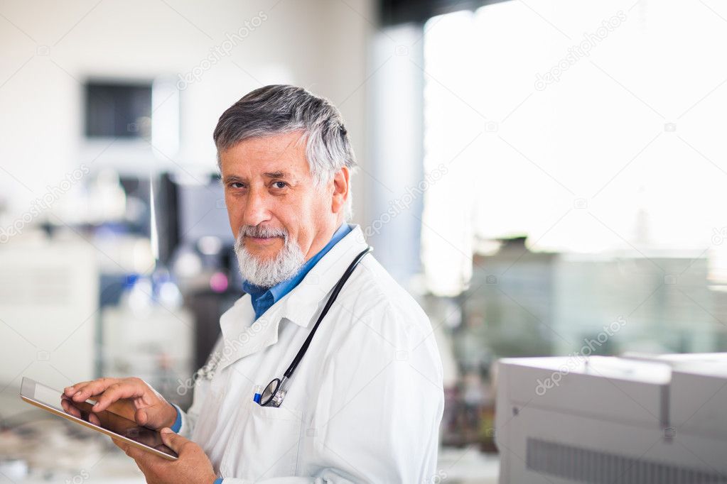 Senior doctor using his tablet computer at work