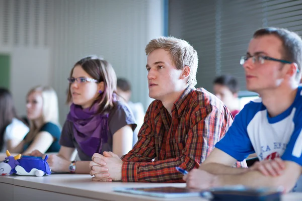 Fiatal, jóképű főiskolai hallgató ül egy osztályteremben — Stock Fotó