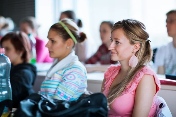Ung, ganska kvinnlig collegestudent som sitter i ett klassrum — Stockfoto