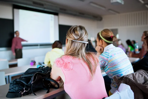Ung, pen, kvinnelig collegestudent som sitter i et klasserom – stockfoto