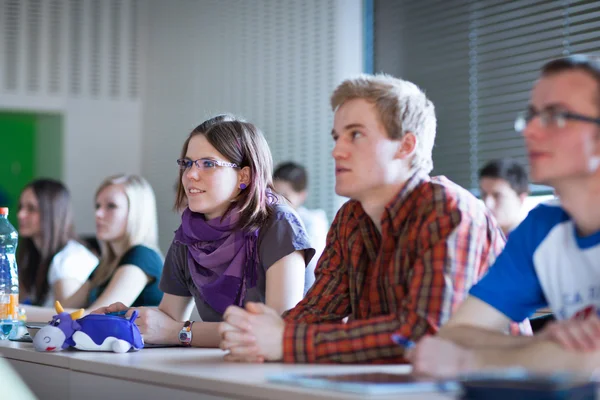 Joven y guapo estudiante universitario sentado en un salón de clases — Foto de Stock