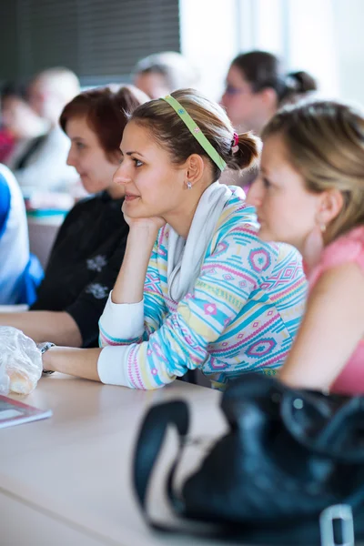 Joven, bonita estudiante universitaria sentada en un salón de clases —  Fotos de Stock