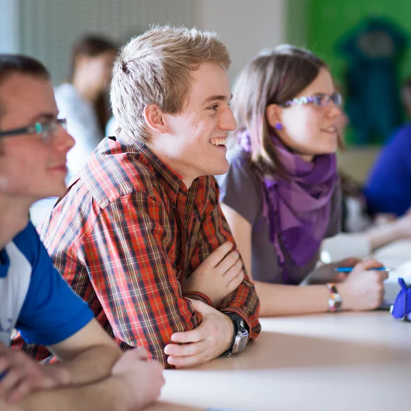 Estudante universitário jovem e bonito sentado em uma sala de aula — Fotografia de Stock