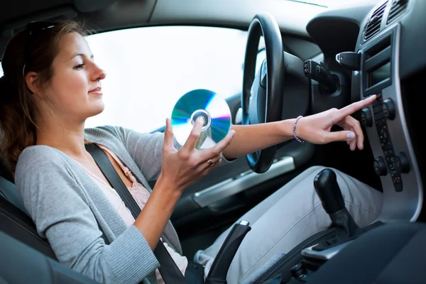 Młodego kierowcy kobiece granie muzyki w samochodzie (zmiana płyty CD) — Zdjęcie stockowe