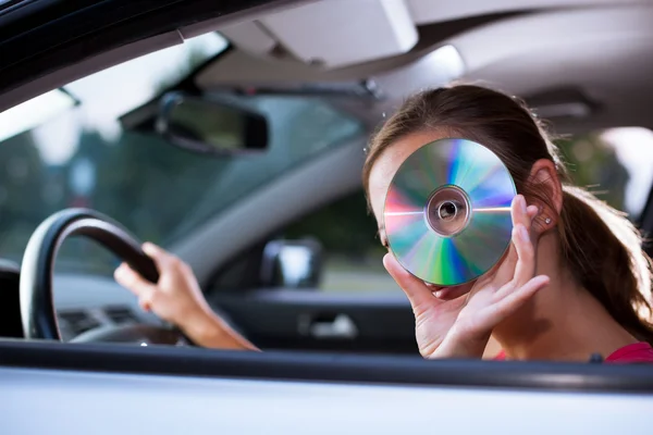 stock image Young female driver playing music in the car (changing CDs)