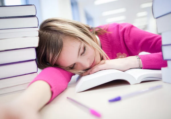 In the library - very tired / exhausted, pretty, female student — стоковое фото