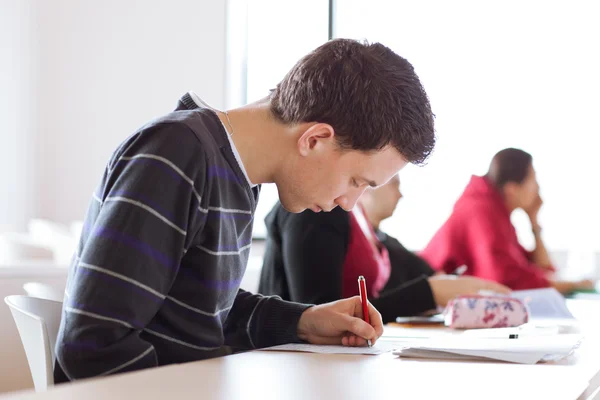 Młody, przystojny mężczyzna kolegium student siedzi w klasie — Zdjęcie stockowe