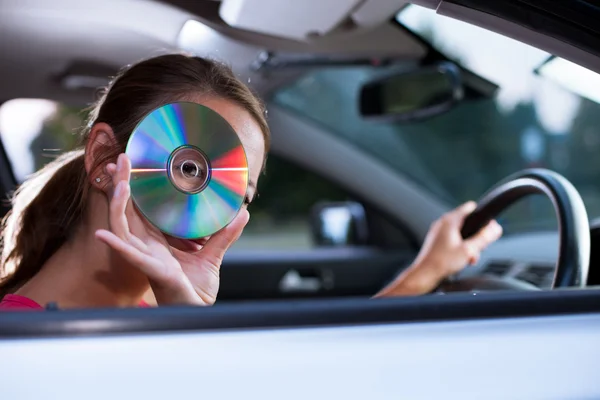 Unga kvinnliga förare spela musik i bilen (ändra CD-skivor) — Stockfoto