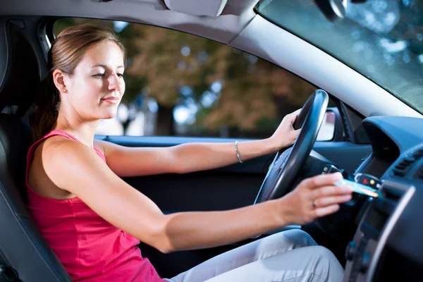 Jonge vrouwelijke bestuurder afspelen van muziek in de auto (het veranderen van cd 's) — Stockfoto
