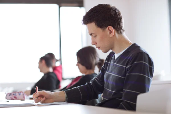 Young, handsome male college student sitting in a classroom — Stock Photo, Image