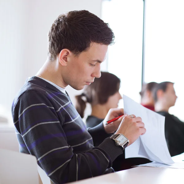 Ung, stilig hane högskolestudent som sitter i ett klassrum — Stockfoto