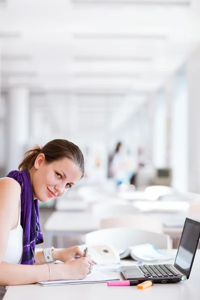Pretty female college student studying in the university library Stock Image