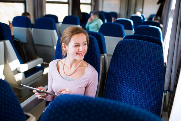 Jeune femme utilisant son ordinateur tablette tout en voyageant en train — Photo