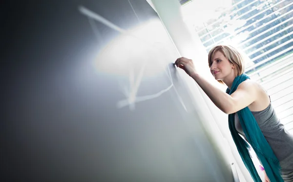 College student/young teacher writing on the chalkboard — Stock Photo, Image