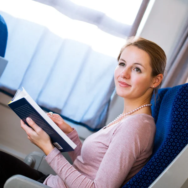 Mujer joven leyendo un libro mientras está en un tren —  Fotos de Stock