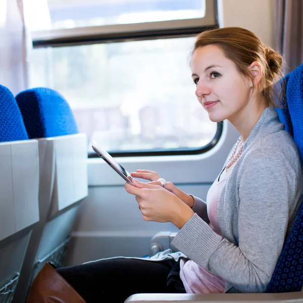 Mujer joven usando su tableta mientras viaja en tren — Foto de Stock