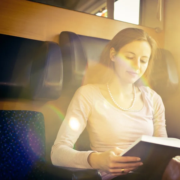Νεαρή γυναίκα διαβάζοντας ένα βιβλίο, ενώ σε ένα τρένο — Φωτογραφία Αρχείου